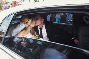 happy romantic newlyweds kissing in wedding limo service