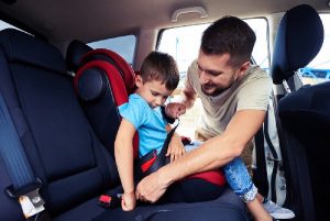 Man securing a child car seat representing kids transportation service in Chicago.