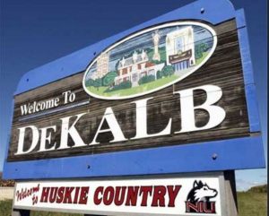 A welcome sign for DeKalb with a cityscape illustration and huskie country for Limo Service DeKalb IL